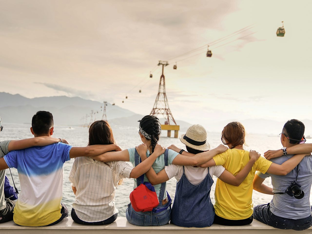 Grupo de amigos sentados de espaldas mirando el mar